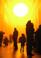 Kunst-Installation: Silhoutten von gelb angestrahltem Publikum vor künstlicher Sonne